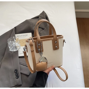 Macro detail of creamy white lychee grain leather bucket bag with brown contrast trim