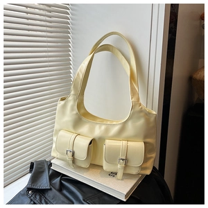 Detail of a large cream tote bag with dual front pockets and metal buckle hardware