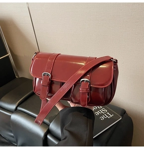 Detail of a vintage dark red patent leather shoulder bag with silver buckle straps