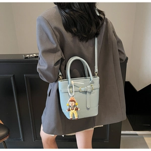 Close-up of light blue lychee pattern bucket bag with a cute cartoon doll pendant