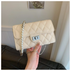 Détail du sac bandoulière matelassé beige avec chaîne en perles et fermoir rotatif argenté