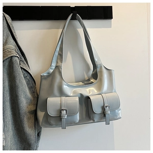 Detail of glossy silver blue shoulder bag featuring dual front pockets and metal buckles
