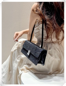 Close-up of elegant black evening bag with rhinestones shown on model in soft lighting
