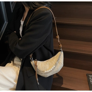 Détail du sac croissant beige avec chaînes en perles et bandoulière marron nouée