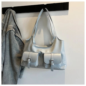Close-up of light blue patent leather tote bag with metallic buckle pockets on a hook