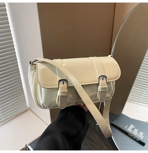 Detail of a retro cream underarm bag with glossy PU finish and metal buckle straps