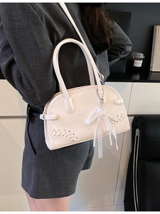 Sac hobo beige chic avec pendentif perle présenté par un mannequin dans un bureau moderne