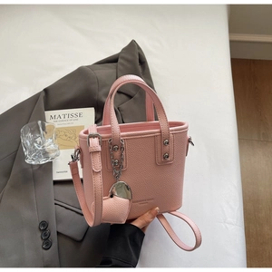 Close-up of pink lychee grain leather bucket bag with silver hardware on white linen