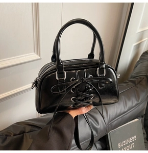 Dettaglio borsa Boston in pelle verniciata nera con fiocco e finiture in metallo argento