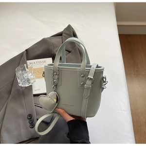 Detail of mint green lychee pattern leather bucket bag with silver heart pendant
