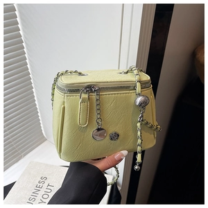 Détail du mini sac boîte vert clair avec bandoulière chaîne et breloque fleur de camélia