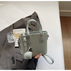 Close-up of mint green leather bucket bag with heart charm and silver rivet details