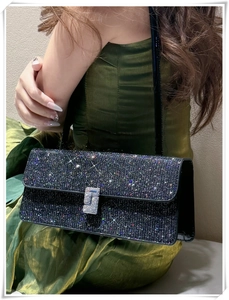 Detailed view of glittering black evening bag with sparkling rhinestone square buckle detail