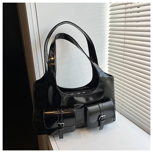 Detail of glossy black hobo bag featuring two front pockets and silver metal buckles