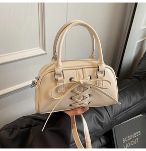Dettaglio della borsa beige in pelle PU con lacci incrociati, fiocco e anelli di metallo