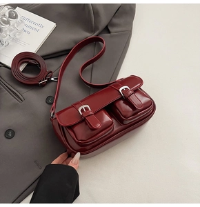 Detail of burgundy glossy patent leather shoulder bag with pockets and silver buckles