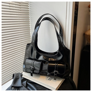 Detail of black glossy patent leather tote bag featuring dual front flap pockets and silver buckles