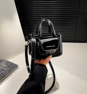 Detail of glossy black patent leather mini bag featuring white FASHION & BAGS text