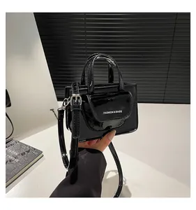 Detail einer glänzenden schwarzen Mini-Tasche mit weißem FASHION & BAGS Schriftzug