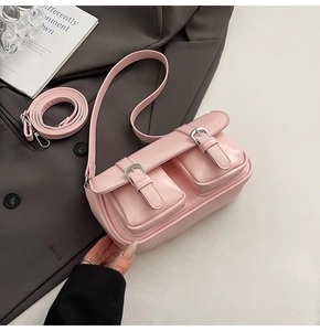 Close-up of light pink leather underarm bag with silver buckles on a grey suit jacket