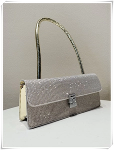 Detail of silver baguette bag with shimmering rhinestones and gold metal handle