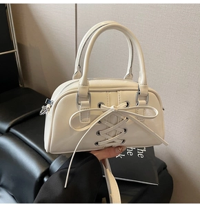 Dettaglio della borsa Boston crema con fiocco decorativo e finitura lucida elegante