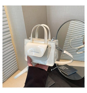 Detail of cream patent leather square bag with front pocket and embossed fashion text