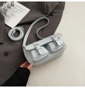 Detail view of light blue PU leather crossbody bag with dual buckled front pockets