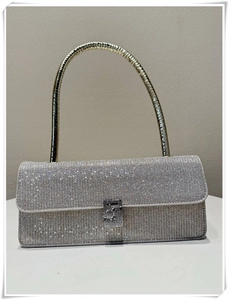 Detail view of a silver rhinestone evening bag with elegant curved gold metal handle