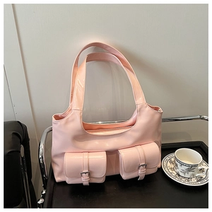 Detail of glossy pink patent leather tote bag featuring two front pockets and silver buckles