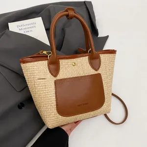 Detailed texture of woven straw tote bag with brown leather pocket and gold buckle