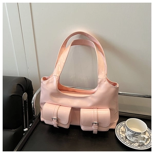 Detail of light pink patent leather shoulder bag with decorative buckle pockets on a tray