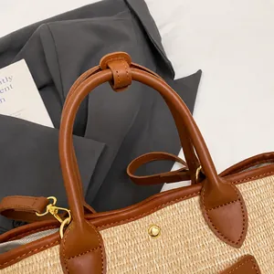 Detail of reinforced brown leather handles with sturdy metal hardware on woven tote bag