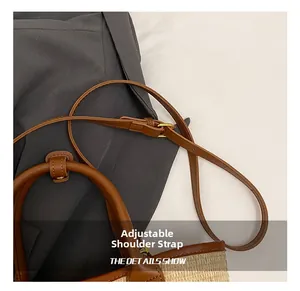 Close-up of the adjustable brown leather strap with metal buckle on woven tote bag