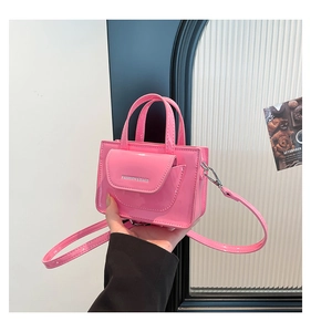 Detail of Barbie pink mini handbag featuring glossy patent leather and decorative flap pocket