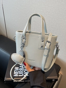 Chic mint green bucket bag in pebble leather with top handles and heart pendant