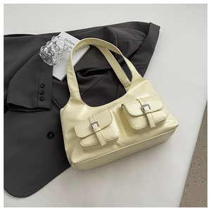 Detail of cream shoulder bag with dual front pockets and silver buckles on a blazer