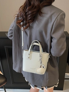 Chic beige lychee leather bucket bag with heart pendant shown in a modern interior setting
