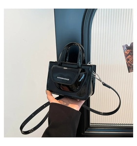 Detail shot of black patent leather small square bag with white FASHION & BAGS lettering