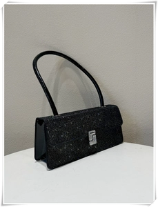 Close-up of black glitter shoulder bag featuring an S-shaped rhinestone buckle detail
