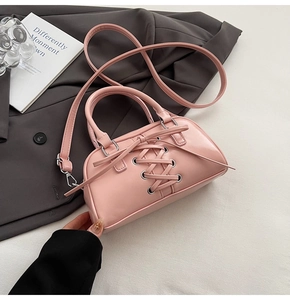 Dettaglio borsa Boston rosa con occhielli argentati, design stringato e tracolla regolabile