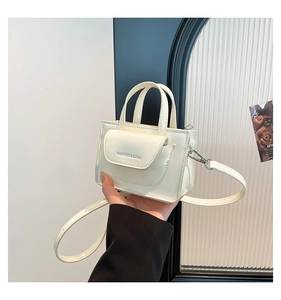 Detail of a creamy white patent leather crossbody bag with Fashion & Bags lettering