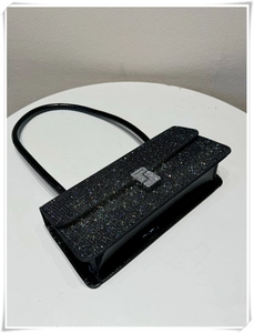 Detail of black sequined underarm bag with shimmering texture and glossy patent leather