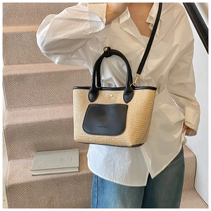 Detail of woven straw tote bag with black leather pockets and detachable shoulder strap
