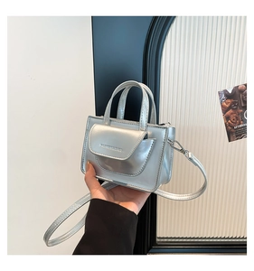 Detail of silver mini crossbody bag with embossed logo and sleek metallic finish
