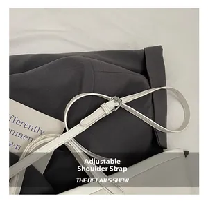 Detail of adjustable white leather shoulder strap with silver metal buckle for bucket bags