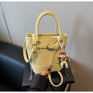 Detail of light yellow lychee grain leather bucket bag with cute character pendant