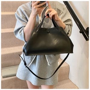 Close-up of black matte tote bag featuring smooth leather texture and sturdy handles