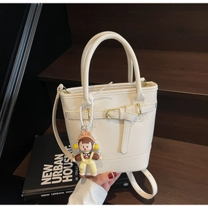 Detailed view of cream white bucket bag with pebble leather texture and a cute charm