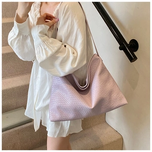 Close-up of lilac woven shoulder bag with leather strap on a model in white blouse
